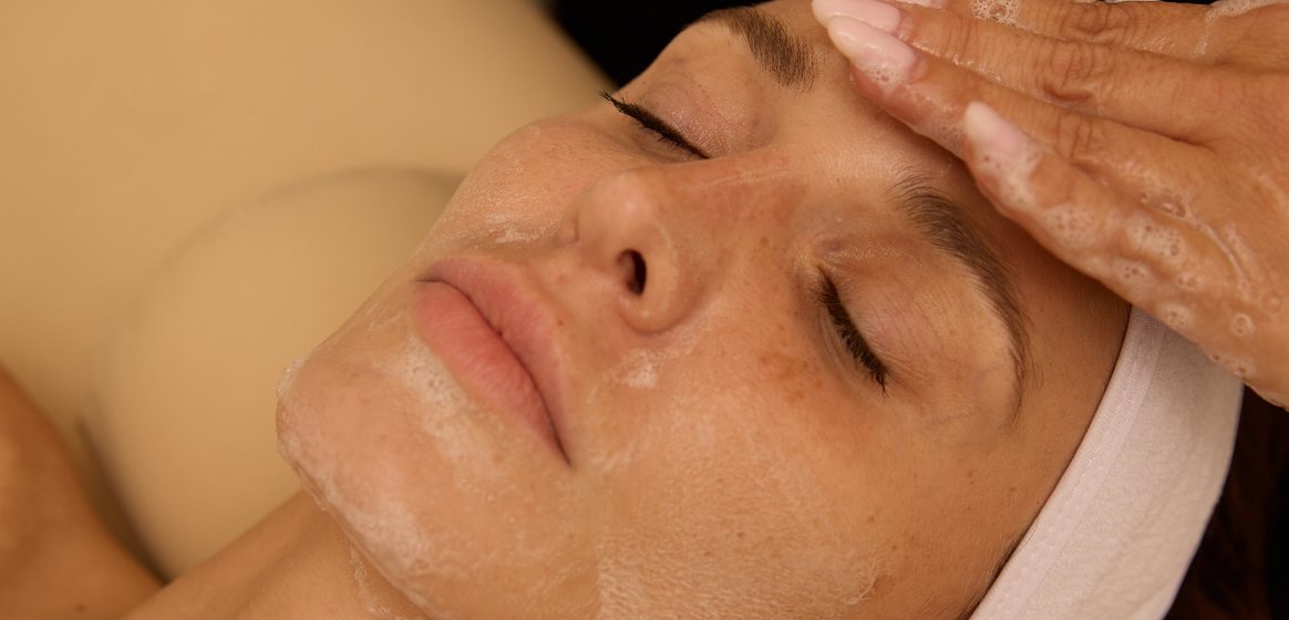 Provider massaging a client’s face during a facial treatment